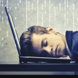 A man with his face resting on the computer keyboard